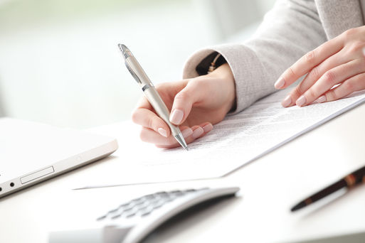 Eine Frau unterzeichnet ein Doklument am Schreibtisch